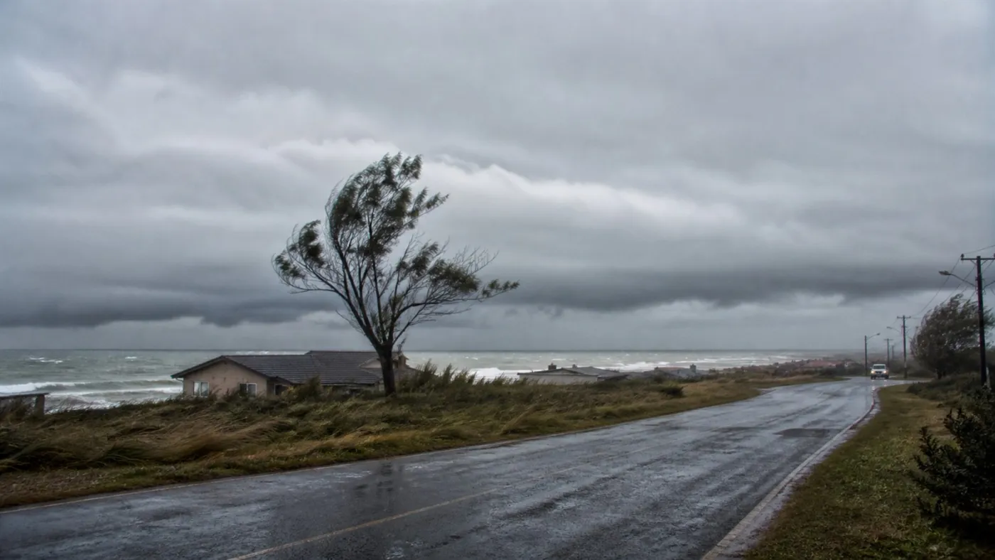 Nuvens de tempestade e vento forte avançam sobre estrada costeira. Imagem ilustrativa gerada por IA para o ClickFato.