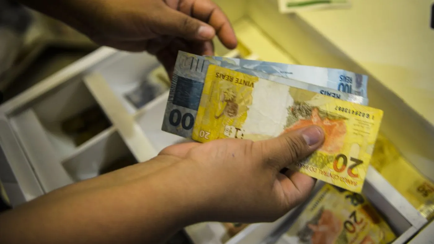 Cédulas de real são retiradas de um caixa eletrônico. Foto: Marcello Casal Jr./Agência Brasil.